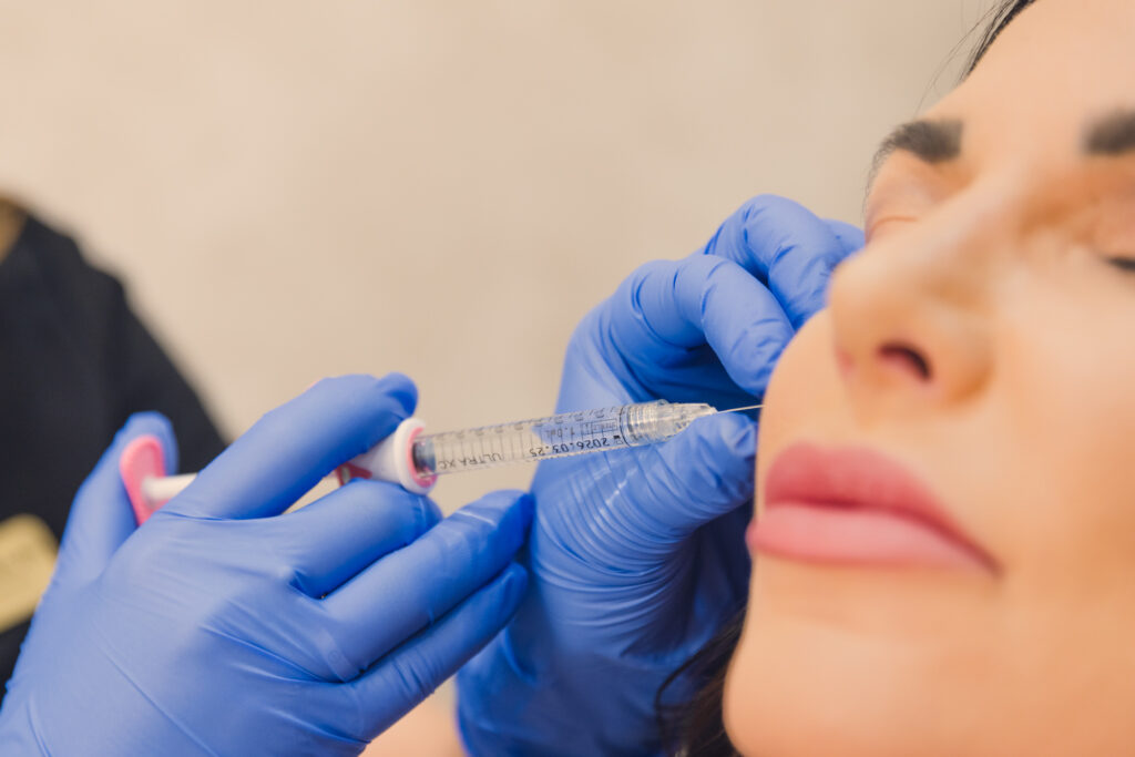 Woman with eye closed relaxes face as a med spa provider injects her cheek with Botox in Summerlin South.